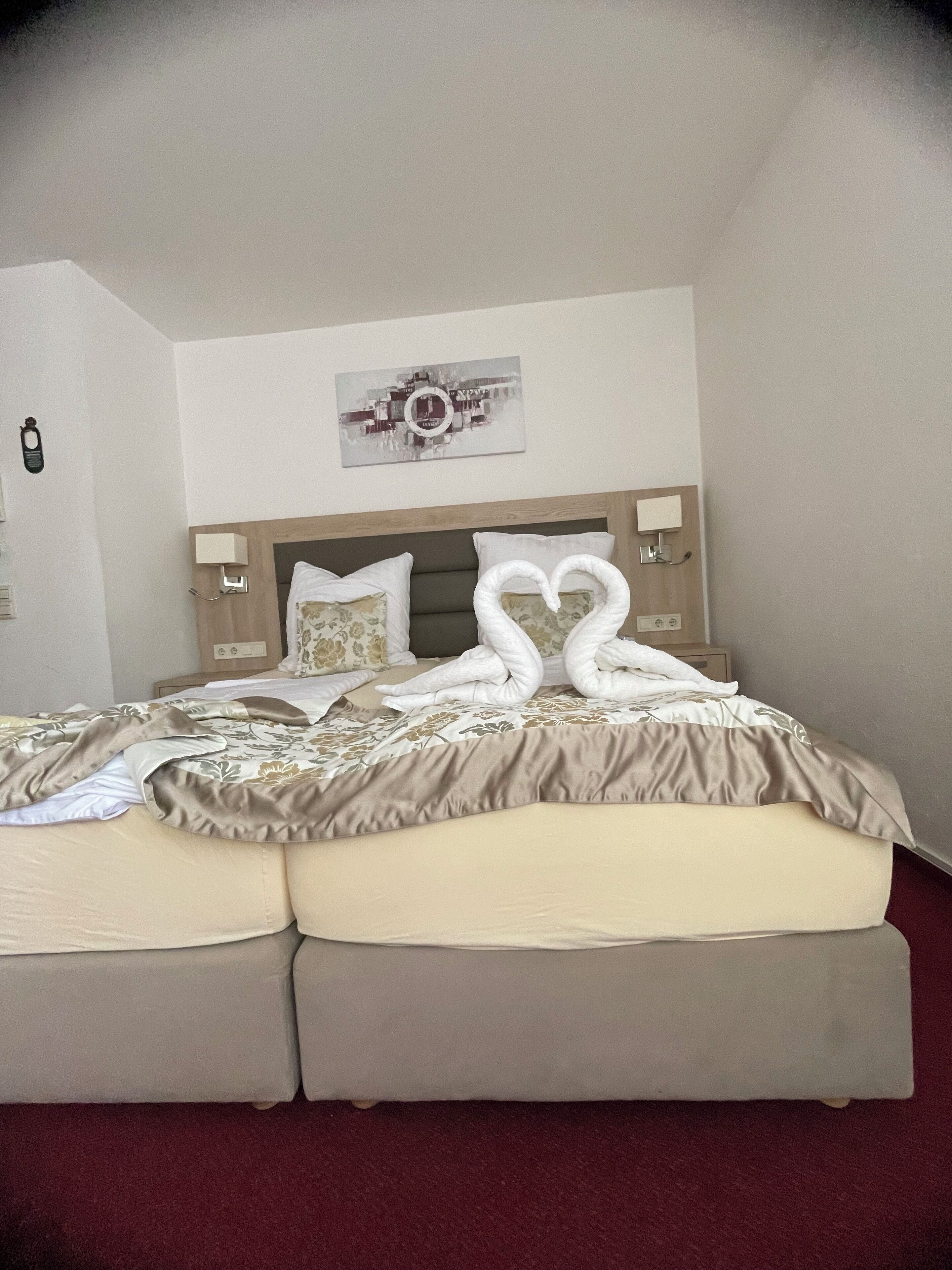 Ein Hotelzimmer mit Bett, Kopfteil, Wandbild und Nachttisch.