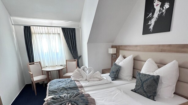 Una camera d'albergo con un letto grande, una scrivania, una sedia e una finestra con tende.