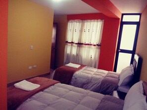 A hotel room with two beds, a window with curtains, and a door leading to another room. - Apu Raymi (Cusco)