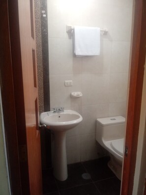 A bathroom with a white sink, toilet, and a towel hanging on the wall. - Apu Raymi (Cusco)