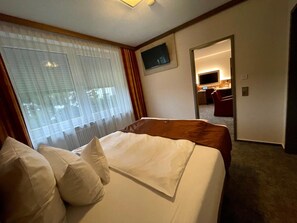 A hotel room with a bed, a TV mounted on the wall, and a view of the hallway.