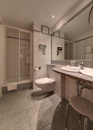 A modern bathroom with a shower, toilet, and sink.