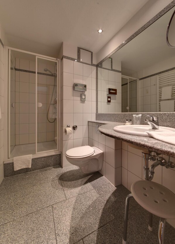 A modern bathroom with a shower, toilet, and sink.