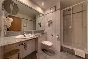 Une salle de bain avec deux lavabos, des toilettes et une douche.