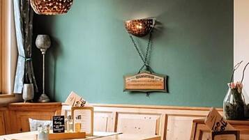 A wooden dining area with a bench and chairs, a table with a menu, and pendant lights.