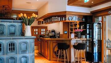 Une cuisine avec des meubles bleus, un réfrigérateur et un coin bar équipé de tabourets.
