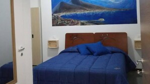 A bedroom with a bed, a night sky painting, and a nightstand. - Domus 19 (Naples)