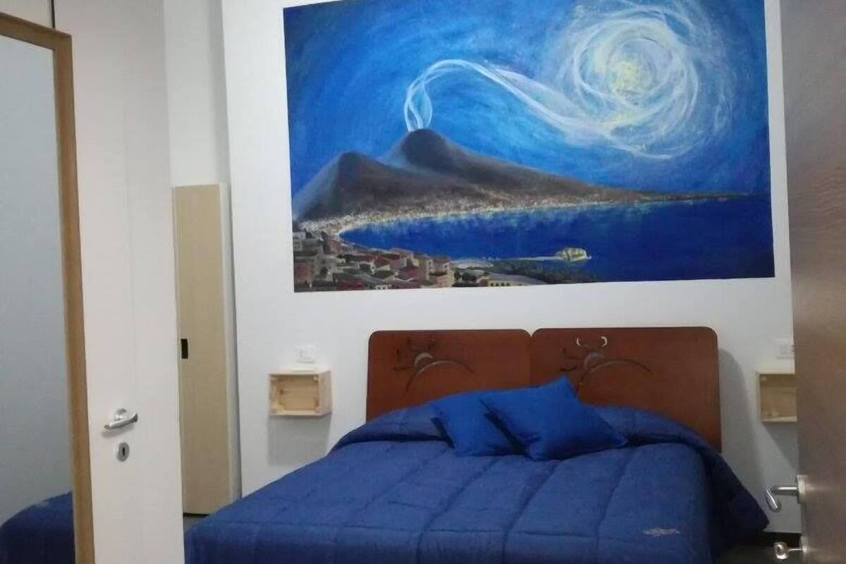 A bedroom with a bed, a night sky painting, and a nightstand.