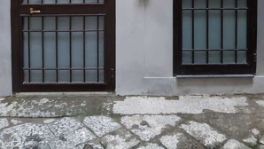 A building with two arched windows, each with a metal grid and a door. - Domus 19 (Naples)