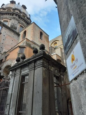Un edificio antiguo con arquitectura clásica, que incluye una cúpula y ventanas arqueadas. Se ve un cartel que dice 'Domus 19' con información de contacto.