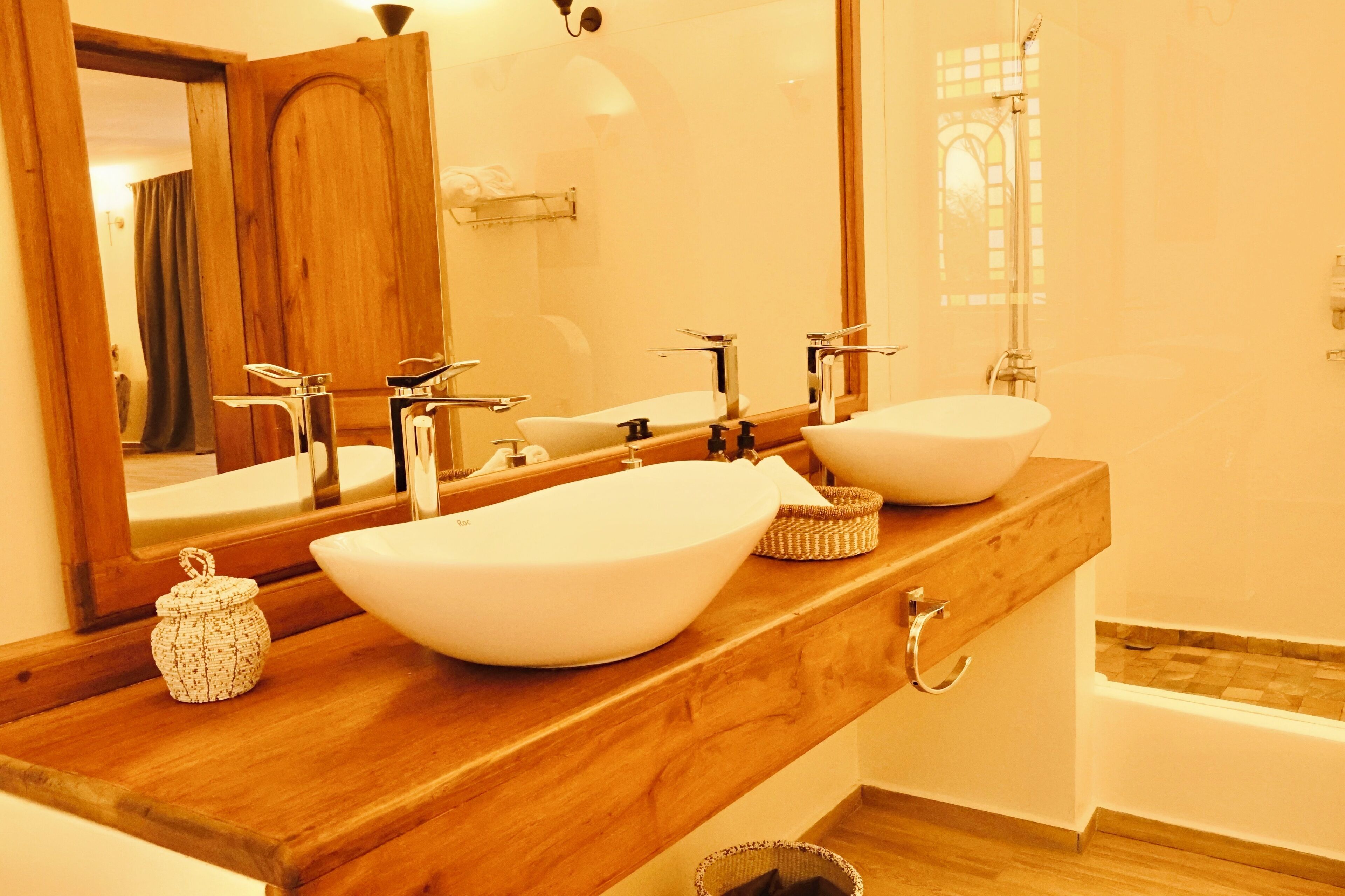 A bathroom with two white vessel sinks, a wooden countertop, a mirror, and a bathtub.