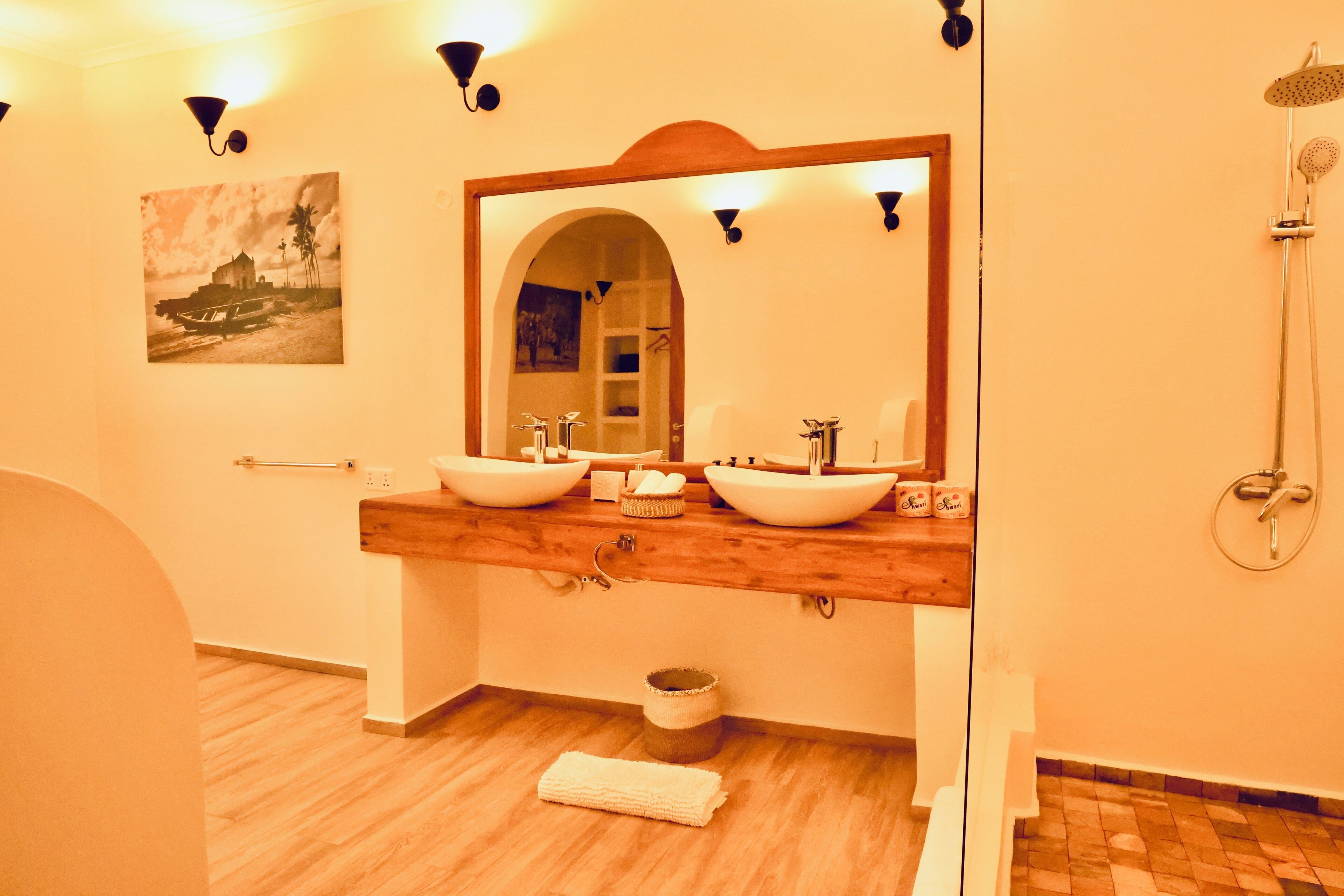 Ein Badezimmer mit zwei Waschbecken, einem großen Spiegel, einer Dusche und einem Holzwaschtisch.