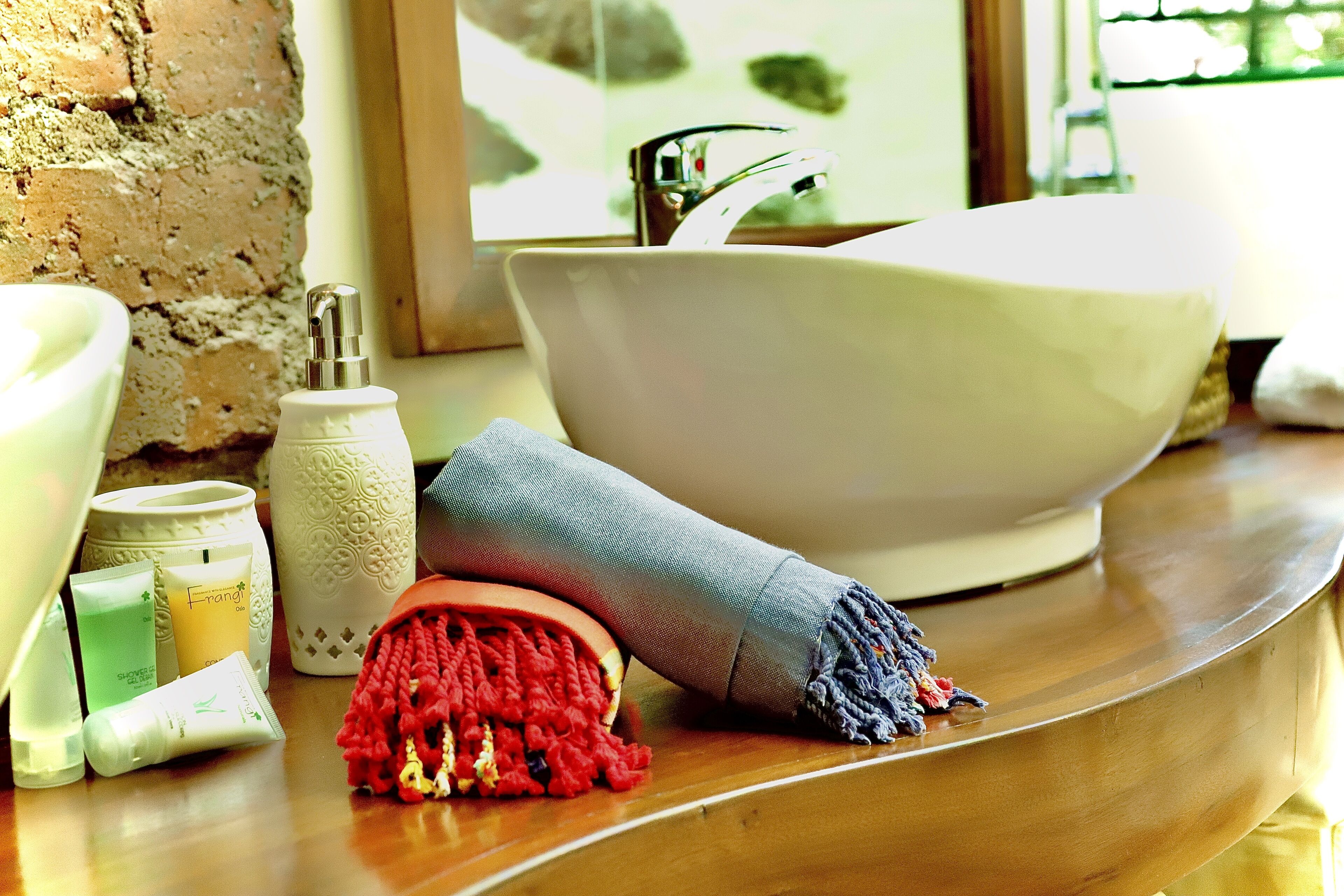 A bathroom with a large white basin, a wooden countertop, and various toiletries.
