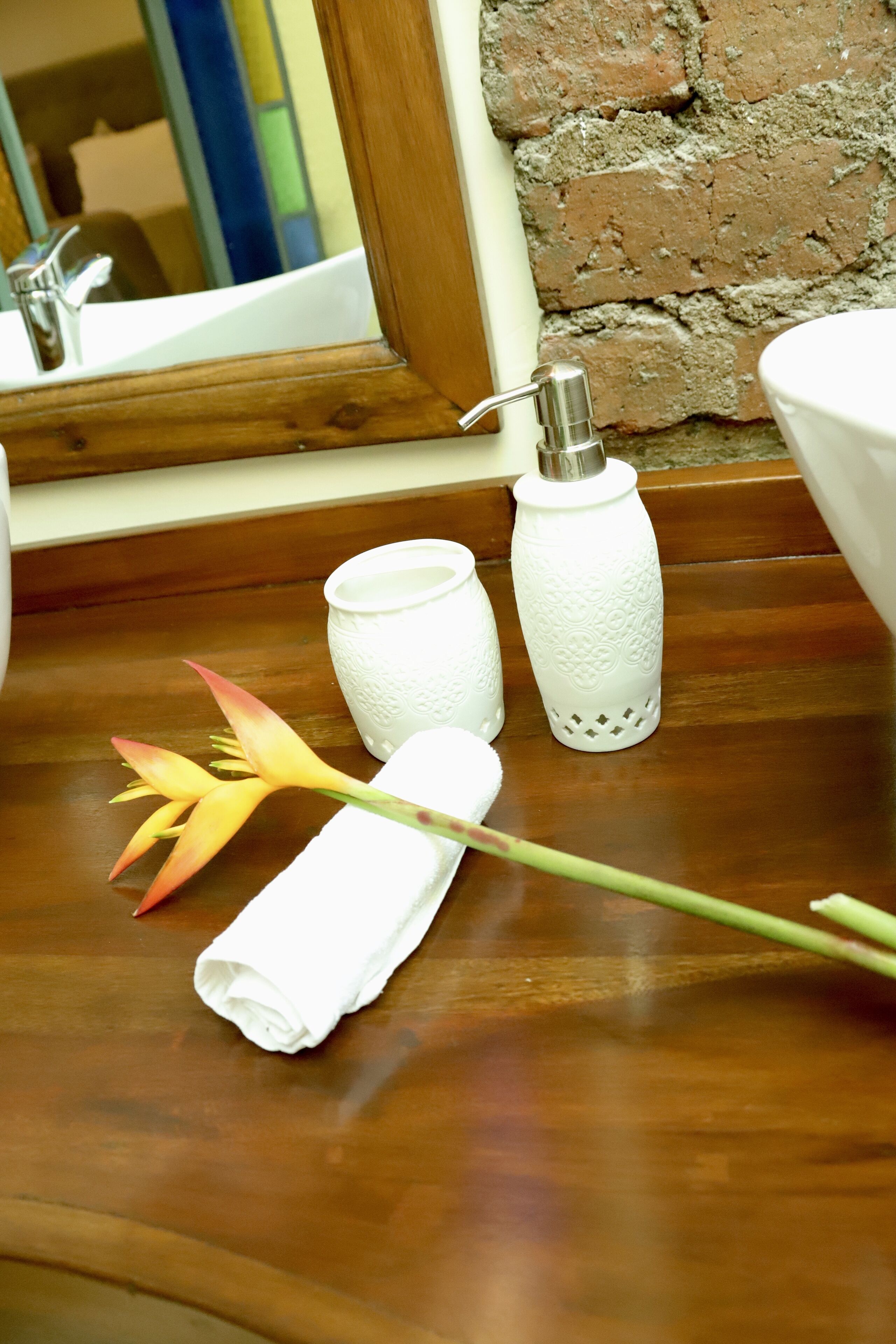 A wooden surface with a white towel, a decorative flower, and two white candle holders.