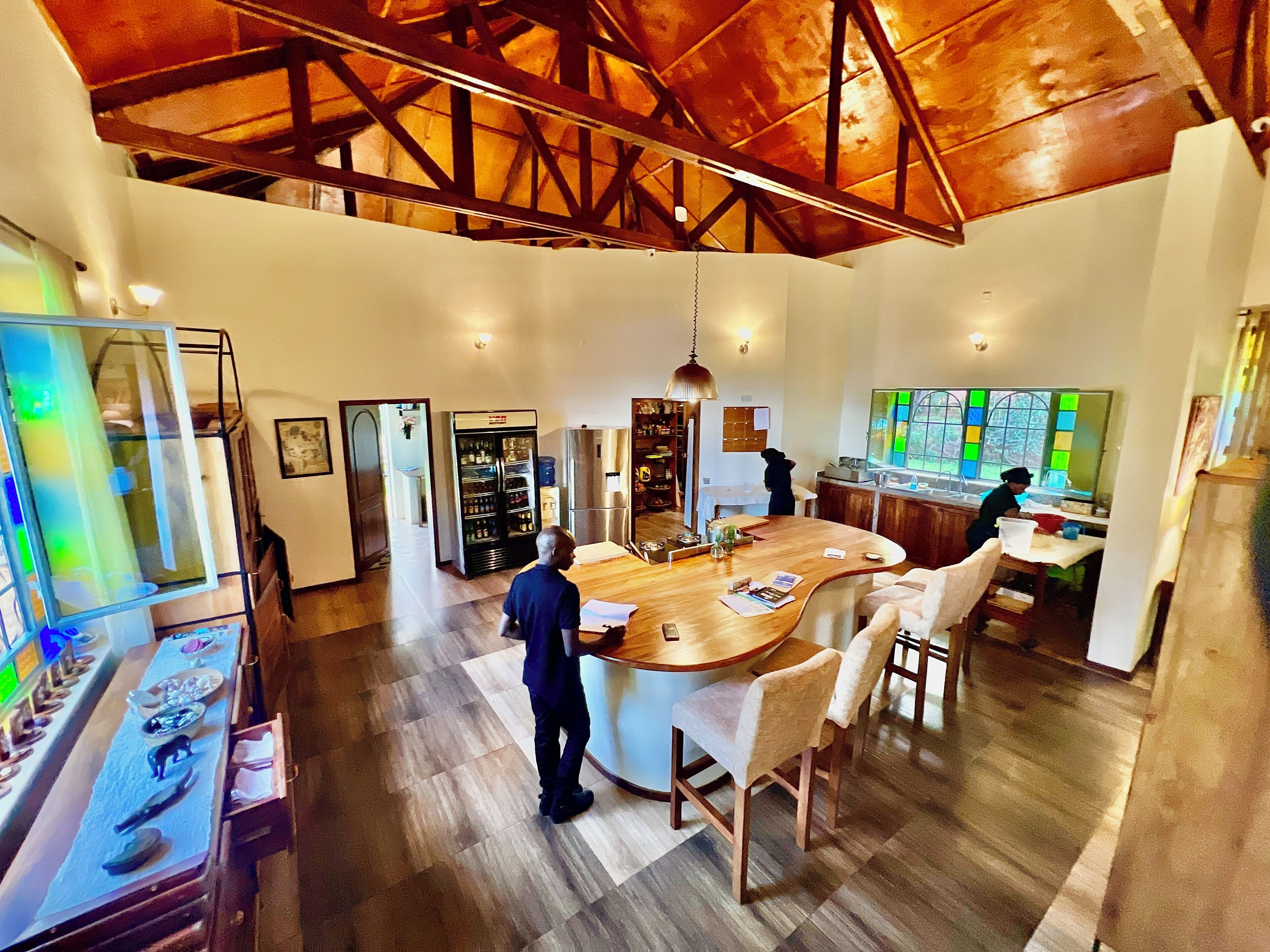 A spacious kitchen with a large island, wooden flooring, and a high ceiling with exposed beams.