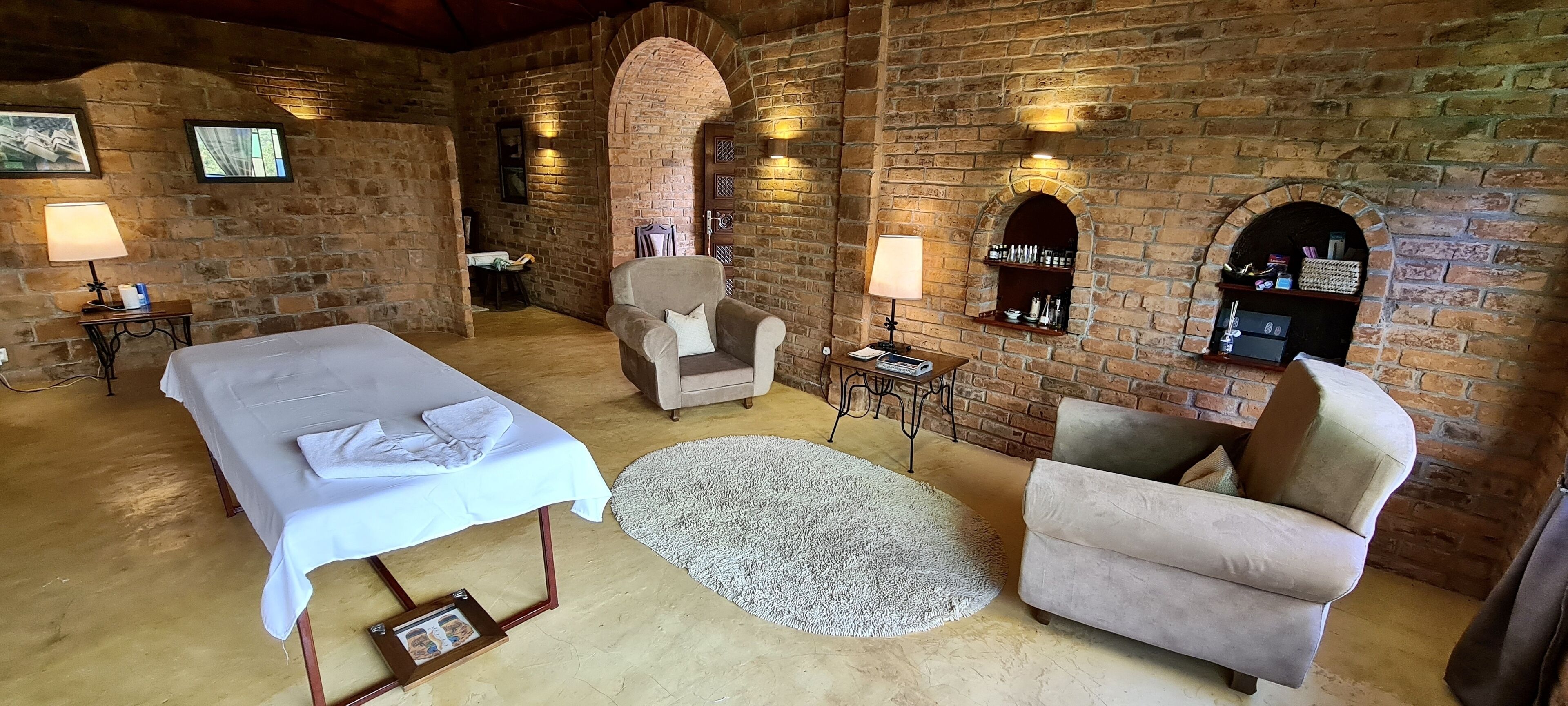 A room with a bed, two armchairs, a small table, and a fireplace.