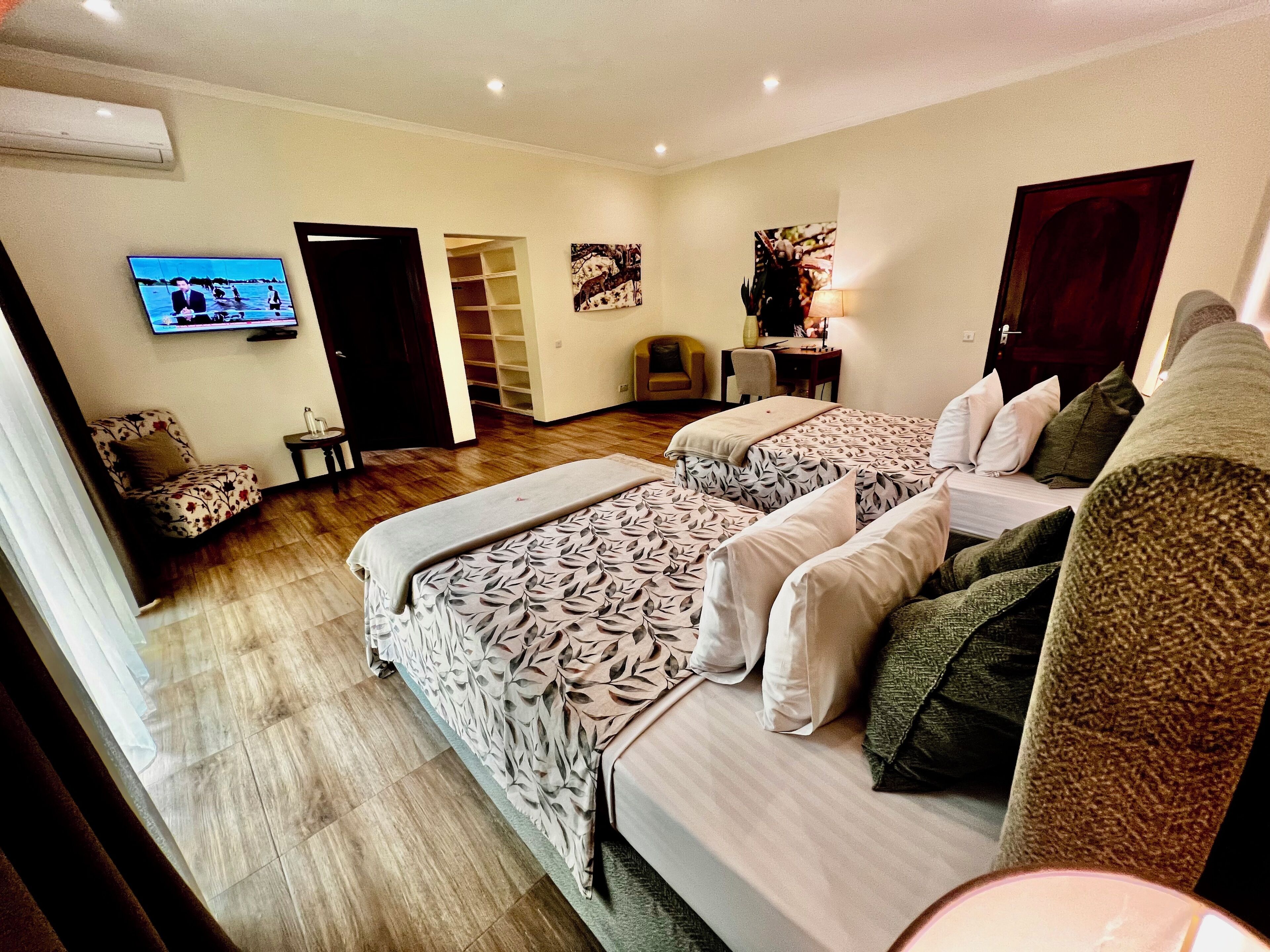 A hotel room with two beds, a TV, a desk, and a chair.