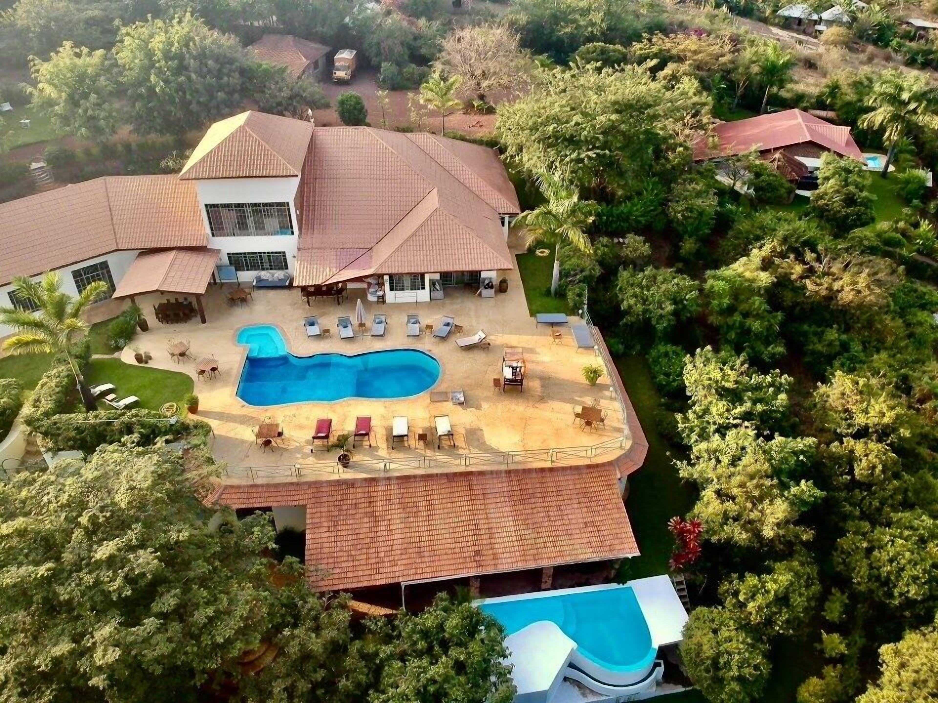 A large house with a swimming pool, outdoor seating, and lush greenery.