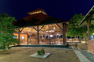 A covered outdoor area with a wooden structure, seating, and a small garden.
