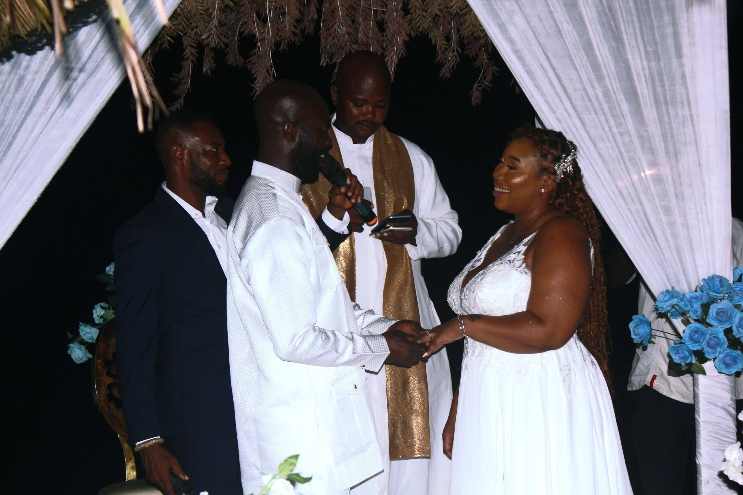 A wedding ceremony with a white and gold altar, floral decorations, and a bouquet of blue roses.