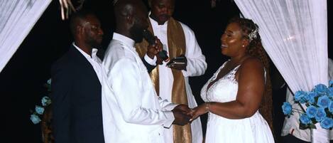 A wedding ceremony with a white and gold altar, floral decorations, and a bouquet of blue roses.