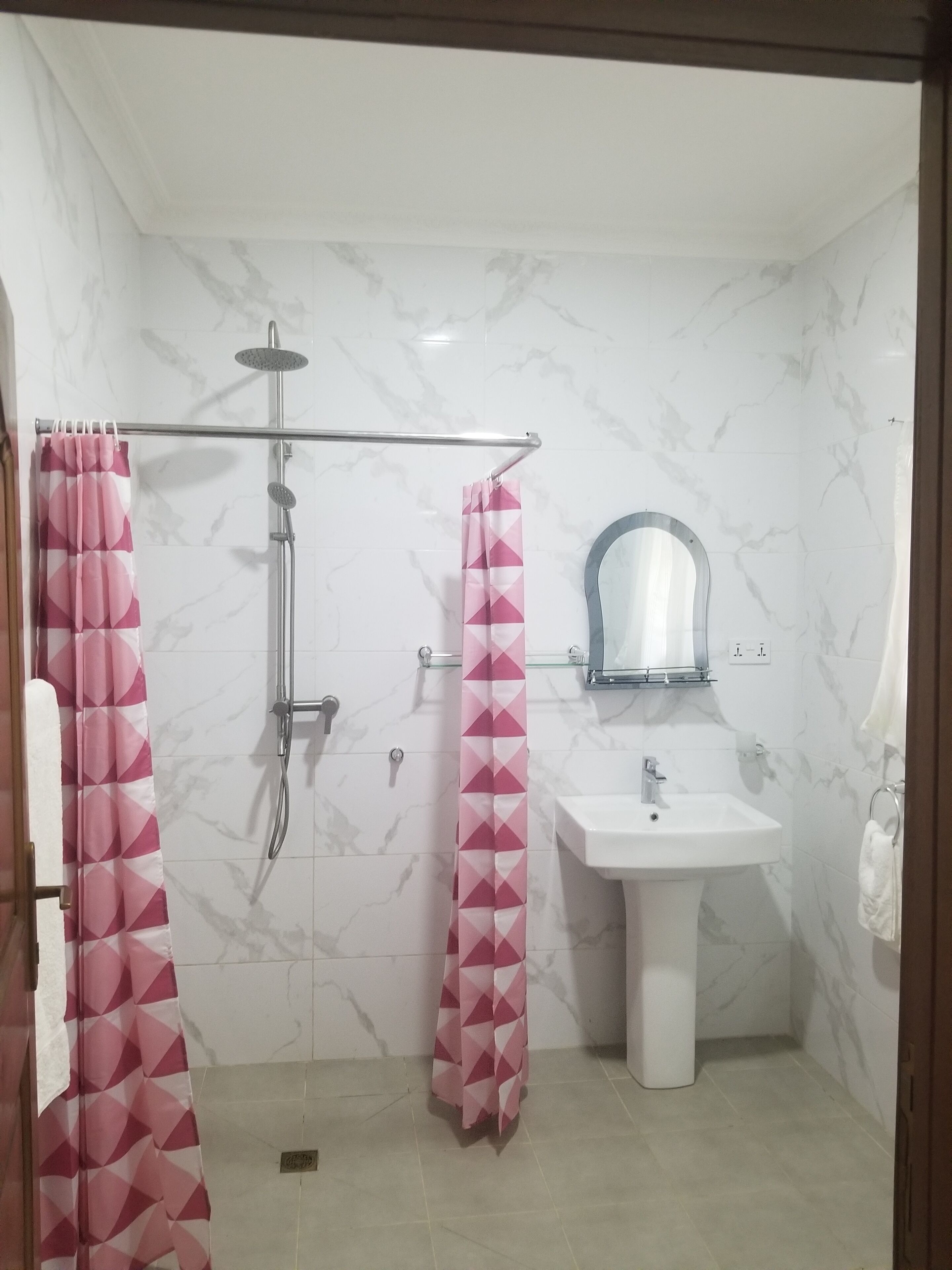 Un baño con ducha, lavamanos y espejo.