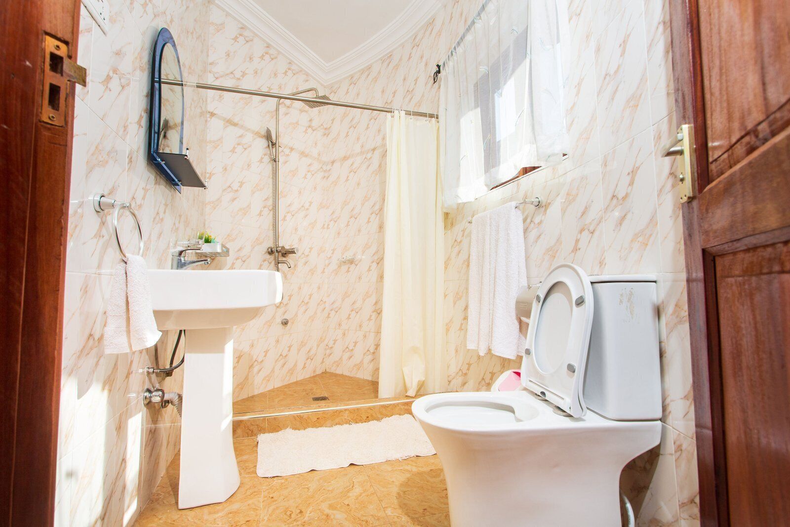 Un baño con inodoro, lavamanos, ducha y espejo.