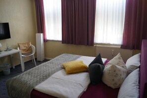 Relax in a cozy space with a comfortable bed, desk, and TV.