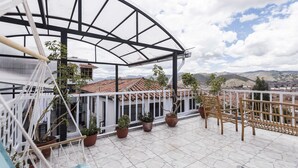 A balcony with a view of the city, potted plants, and a hammock. - Pension Sanbleña B&B (Cusco)