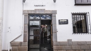 A building entrance with a glass door, a stone base, and a sign above the door. - Pension Sanbleña B&B (Cusco)
