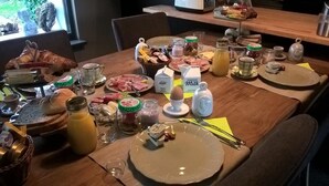 Una mesa de desayuno con diversos alimentos, como pan, huevos y pasteles.