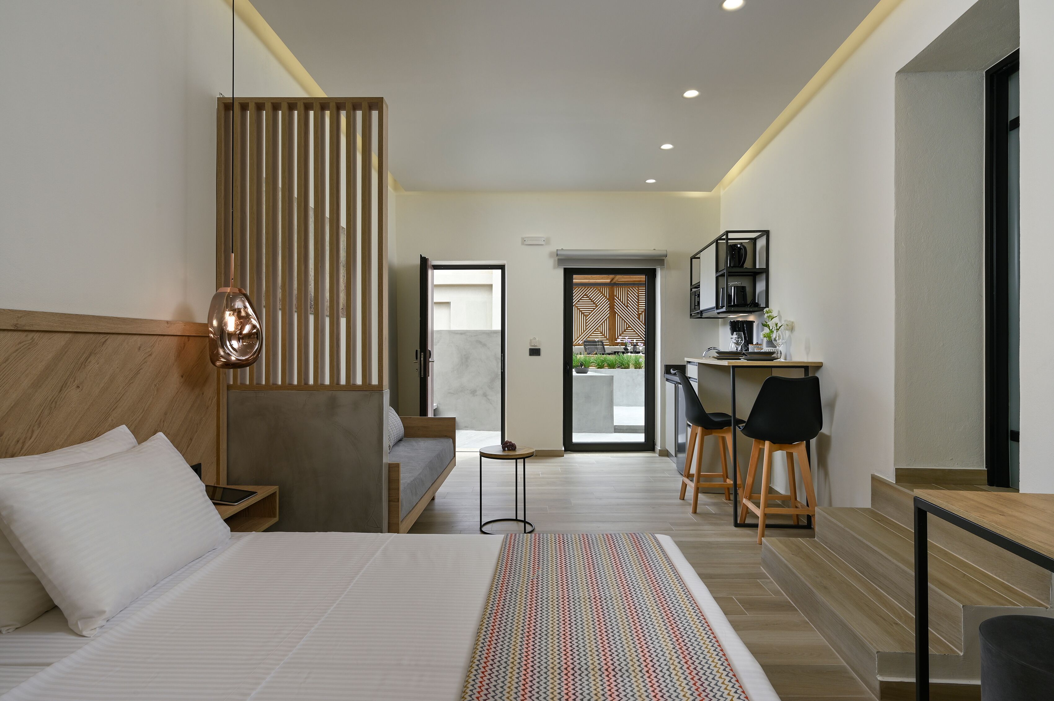 A modern hotel room with a large bed, a desk, and a seating area.