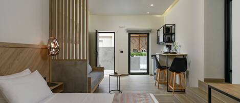 A modern hotel room with a large bed, a desk, and a seating area.