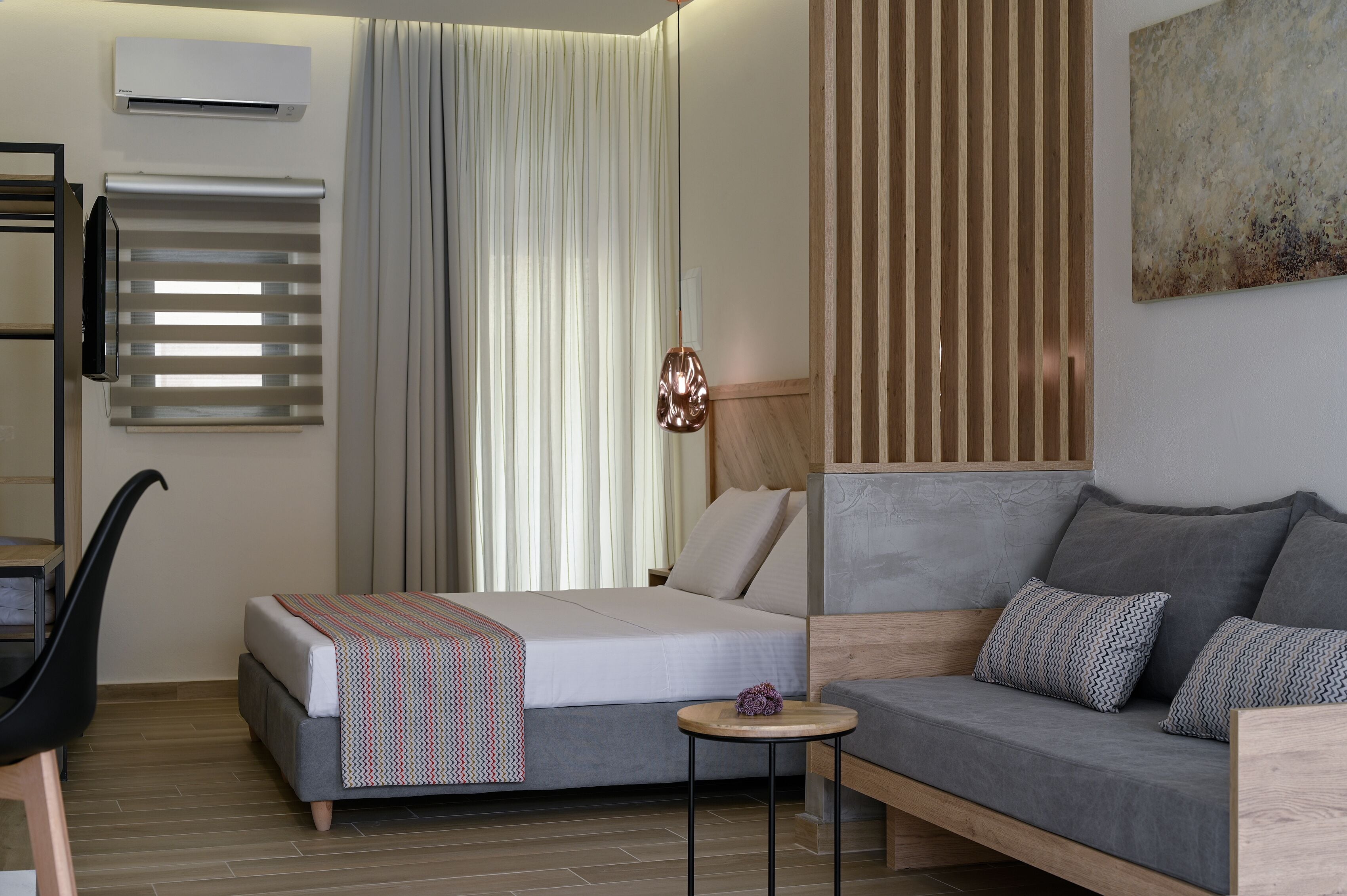 Une chambre d’hôtel moderne, équipée d’un lit, d’un canapé, d’une petite table et d’une chaise.
