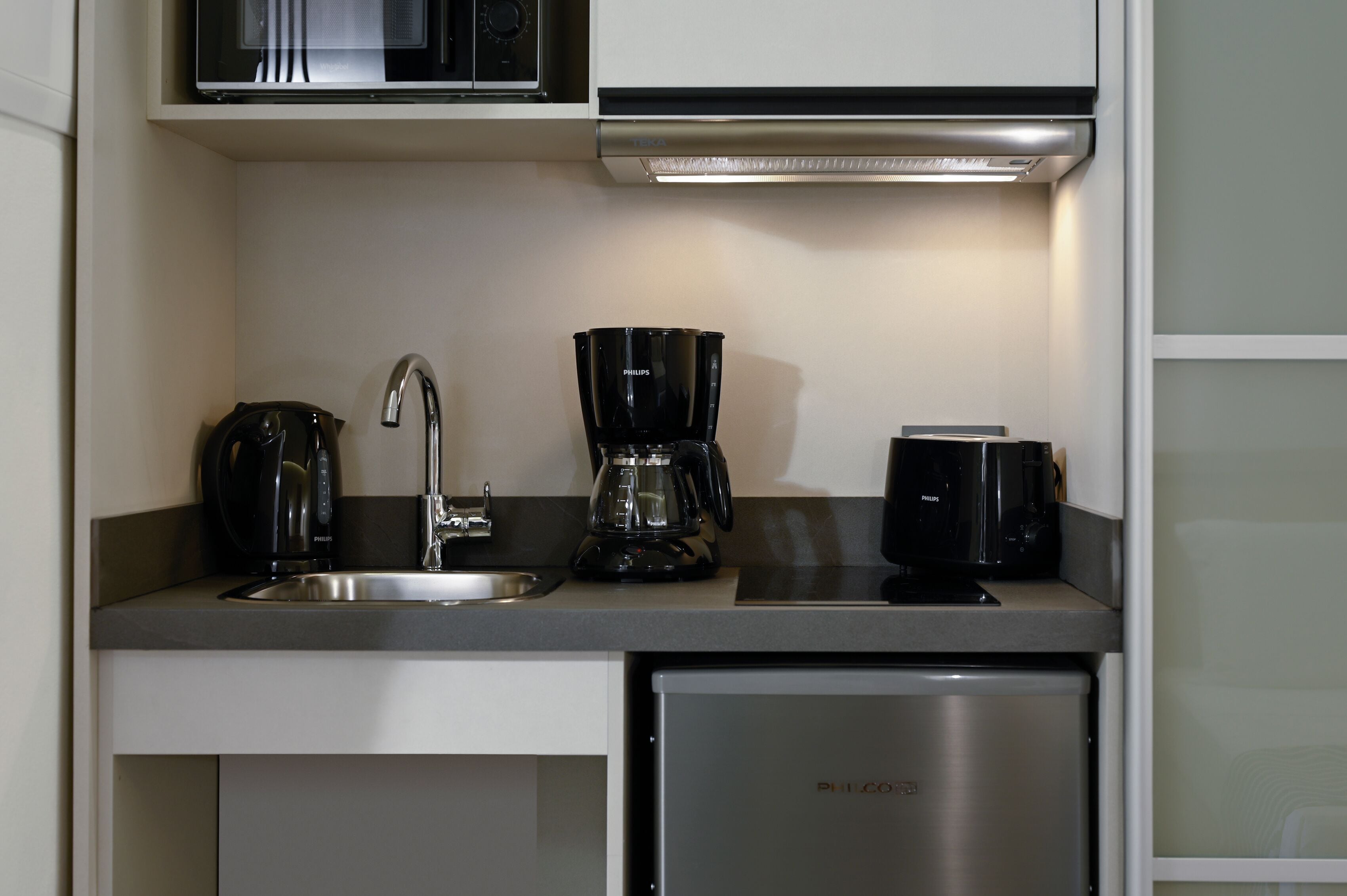 A compact kitchen with a microwave, coffee maker, and toaster on a countertop.