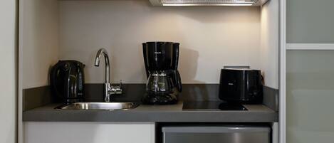 A compact kitchen with a microwave, coffee maker, and toaster on a countertop.
