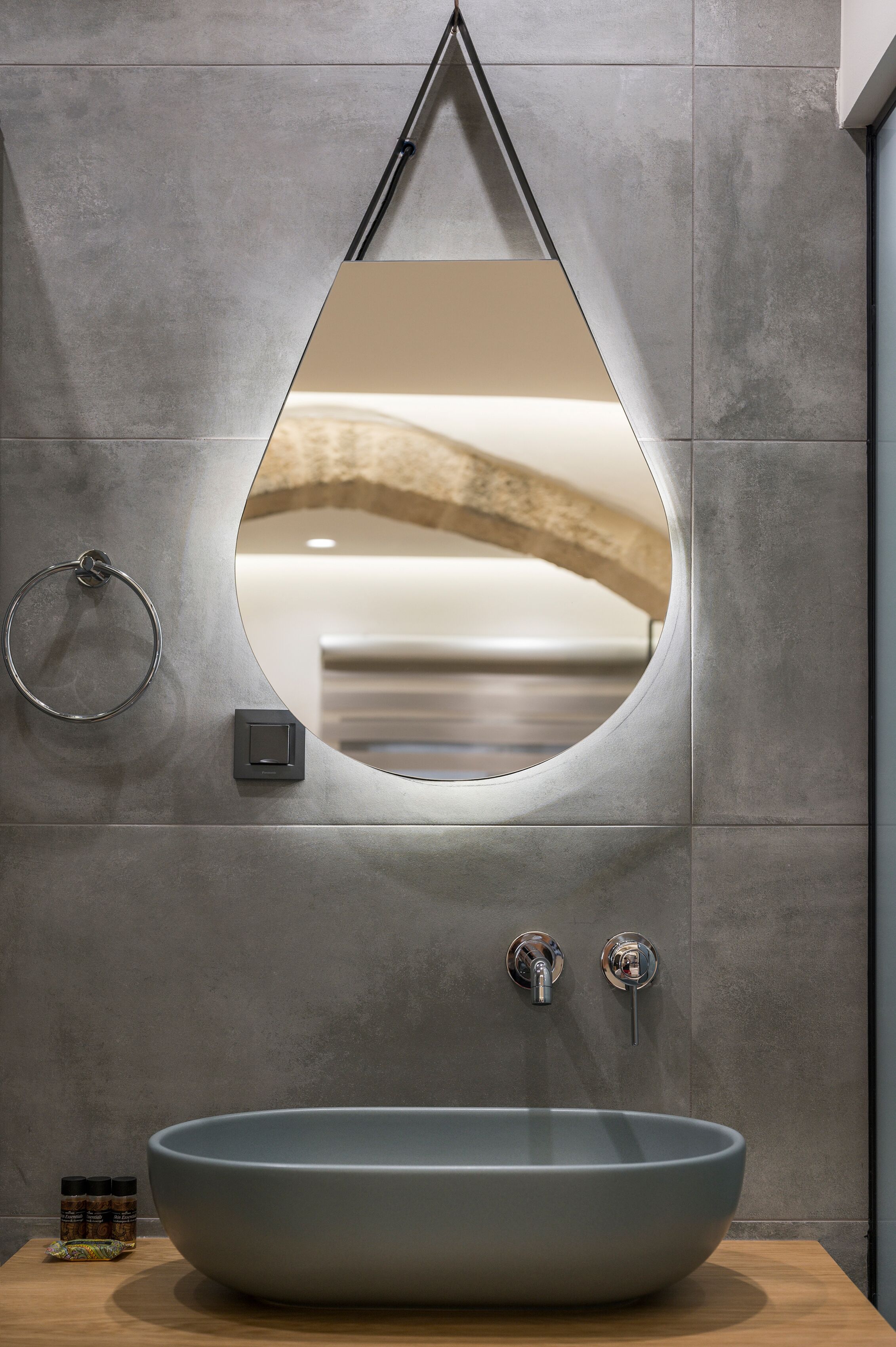 Une salle de bain avec un grand lavabo ovale, un porte-serviettes et un miroir avec un cadre en bois.