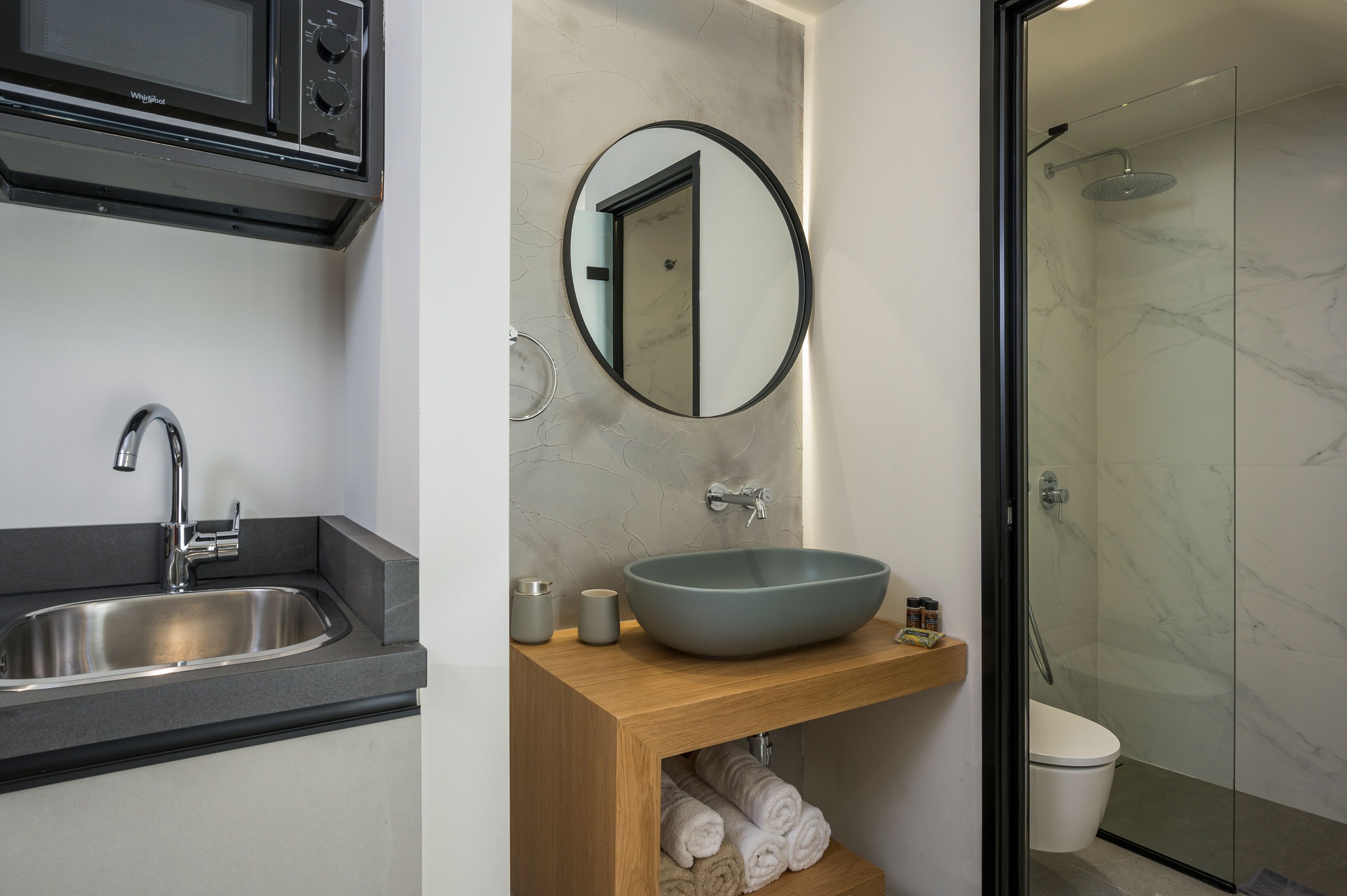 A modern bathroom with a large sink, a mirror, a shower, and a toilet.
