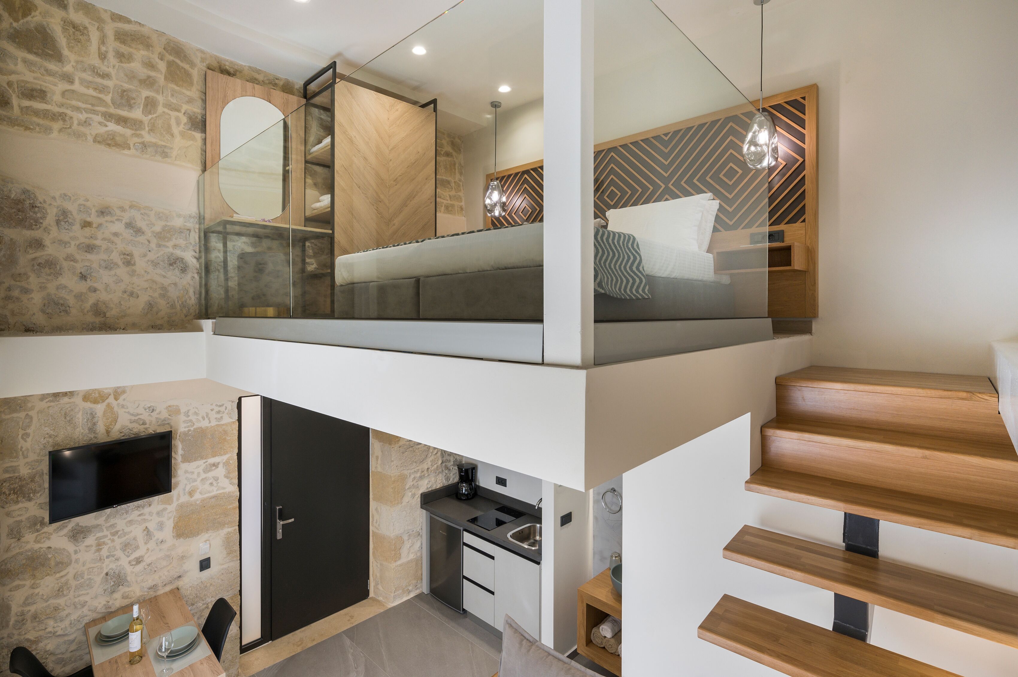 Un appartement moderne de style « loft », comprenant une cuisine, un coin repas et une chambre avec un lit en mezzanine.