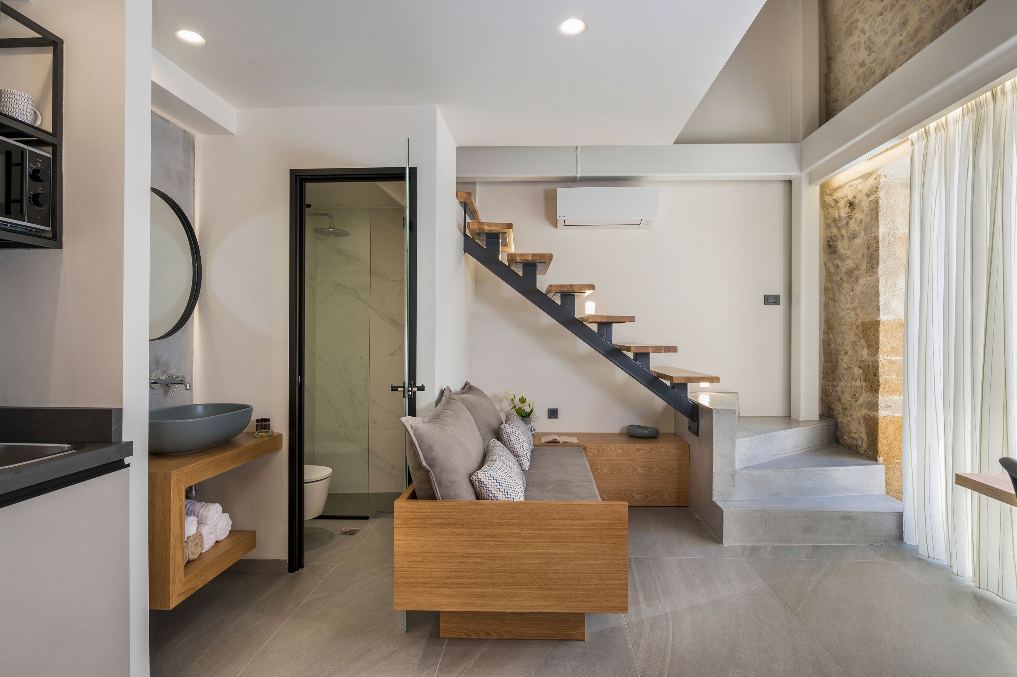 Un interior moderno con un banco de madera, un baño con un lavamanos grande y una escalera.