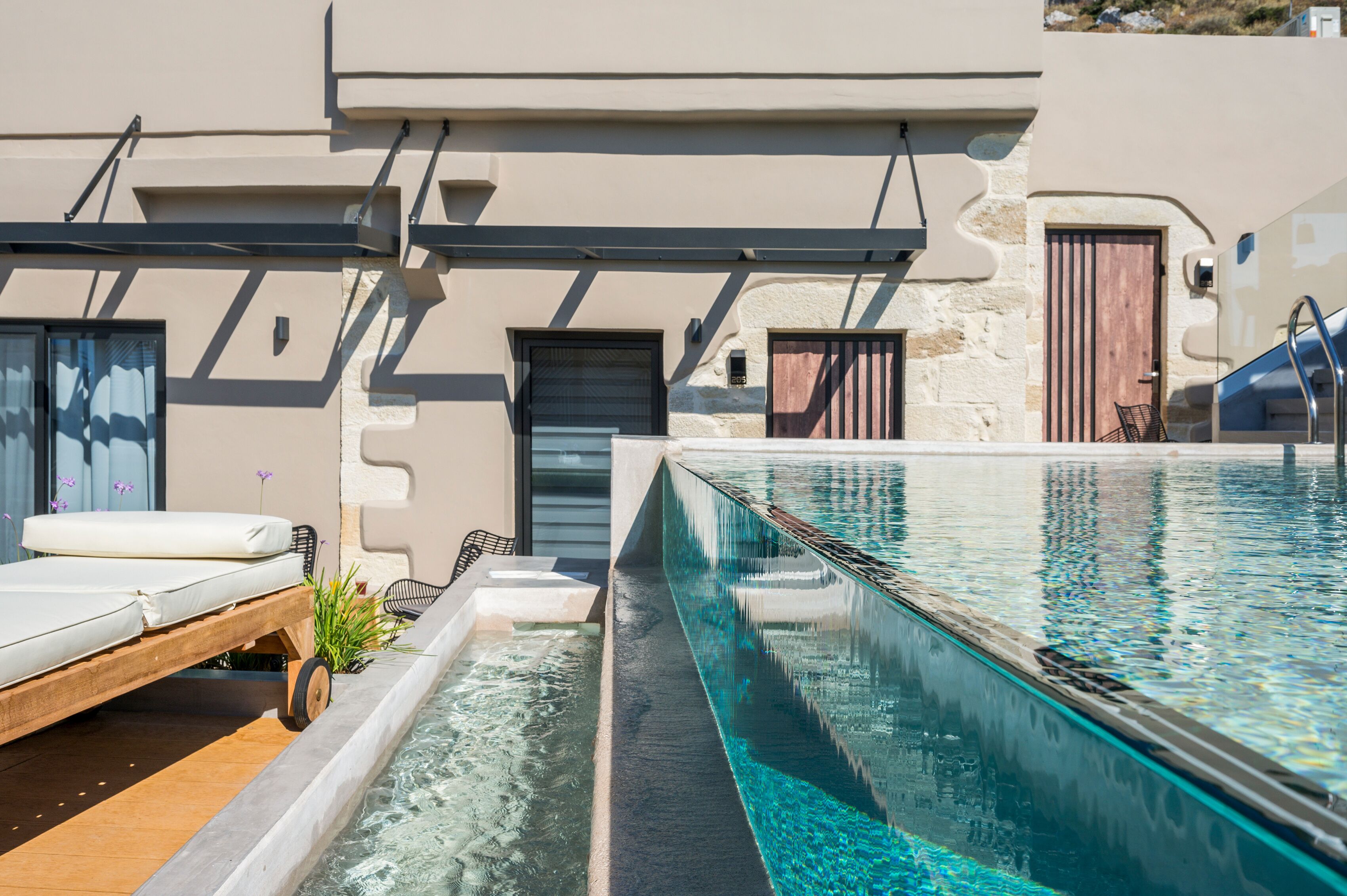 A modern pool area with a lounge chair, a small hot tub, and a clear pool.