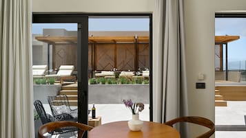 A modern room with a wooden table, chairs, and a view of an outdoor seating area with a geometric wooden pergola and plants.