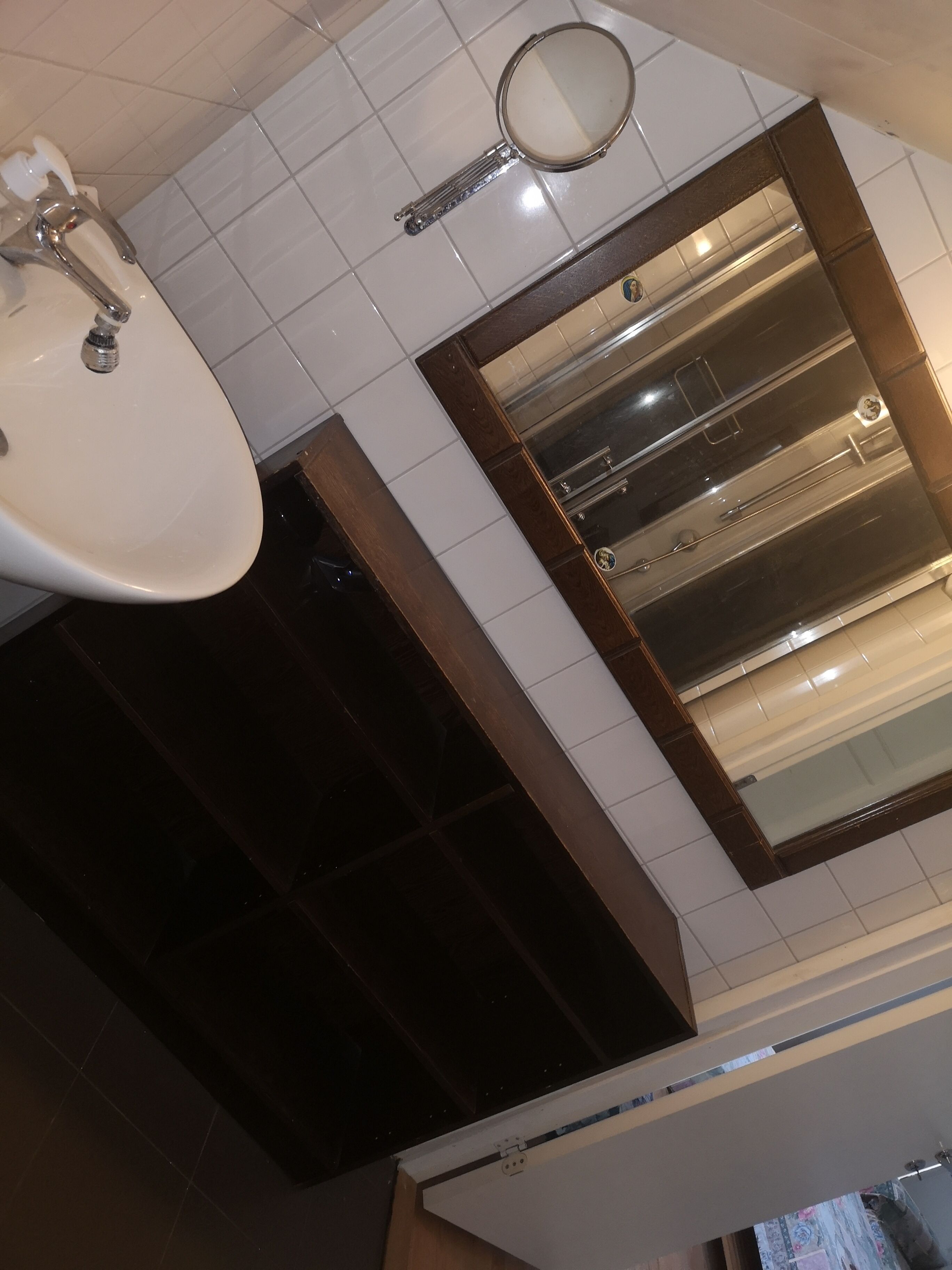 Een badkamer met een wastafel, spiegel en een grote spiegel boven de wastafel.