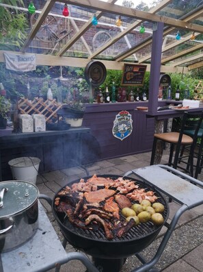 Un espace barbecue extérieur équipé d’un gril, d’un bar et de sièges.
