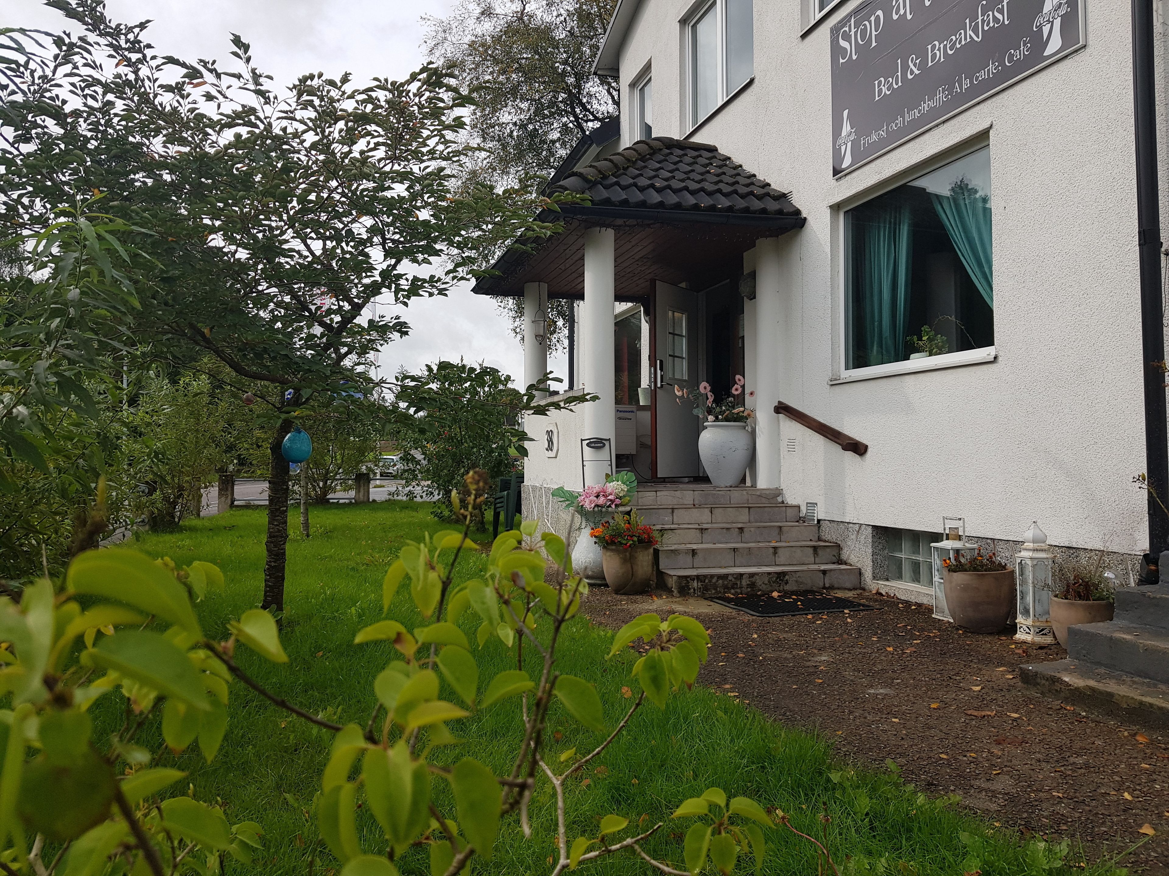 Ein Gebäude mit einem Schild, das es als Bed and Breakfast kennzeichnet, mit einer Veranda, Treppen und Pflanzkübeln.