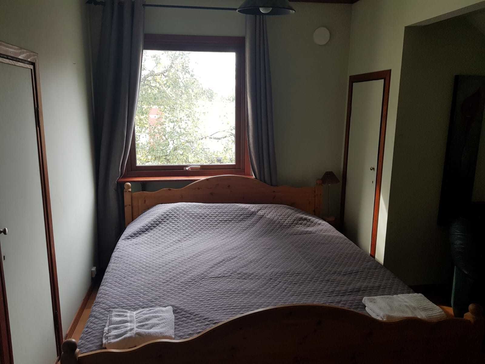 Une petite chambre confortable avec un lit simple, une fenêtre avec des rideaux et un miroir au mur.