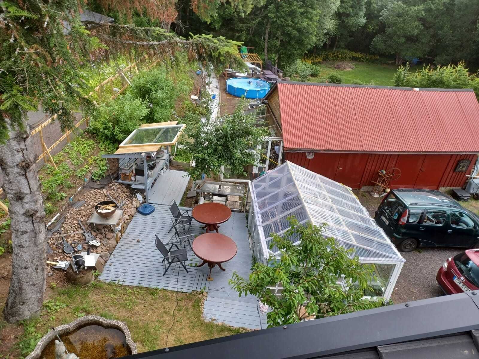 A backyard with a red-roofed shed, a blue pool, and a solar panel structure.