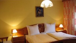 Een kamer met een bed, twee nachtkastjes, een lamp en een schilderij aan de muur.