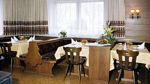 Een restaurant met houten meubels, een kroonluchter en een muur vol wijnflessen.
