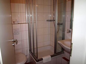 A bathroom with a glass-enclosed shower, a toilet, and a sink.